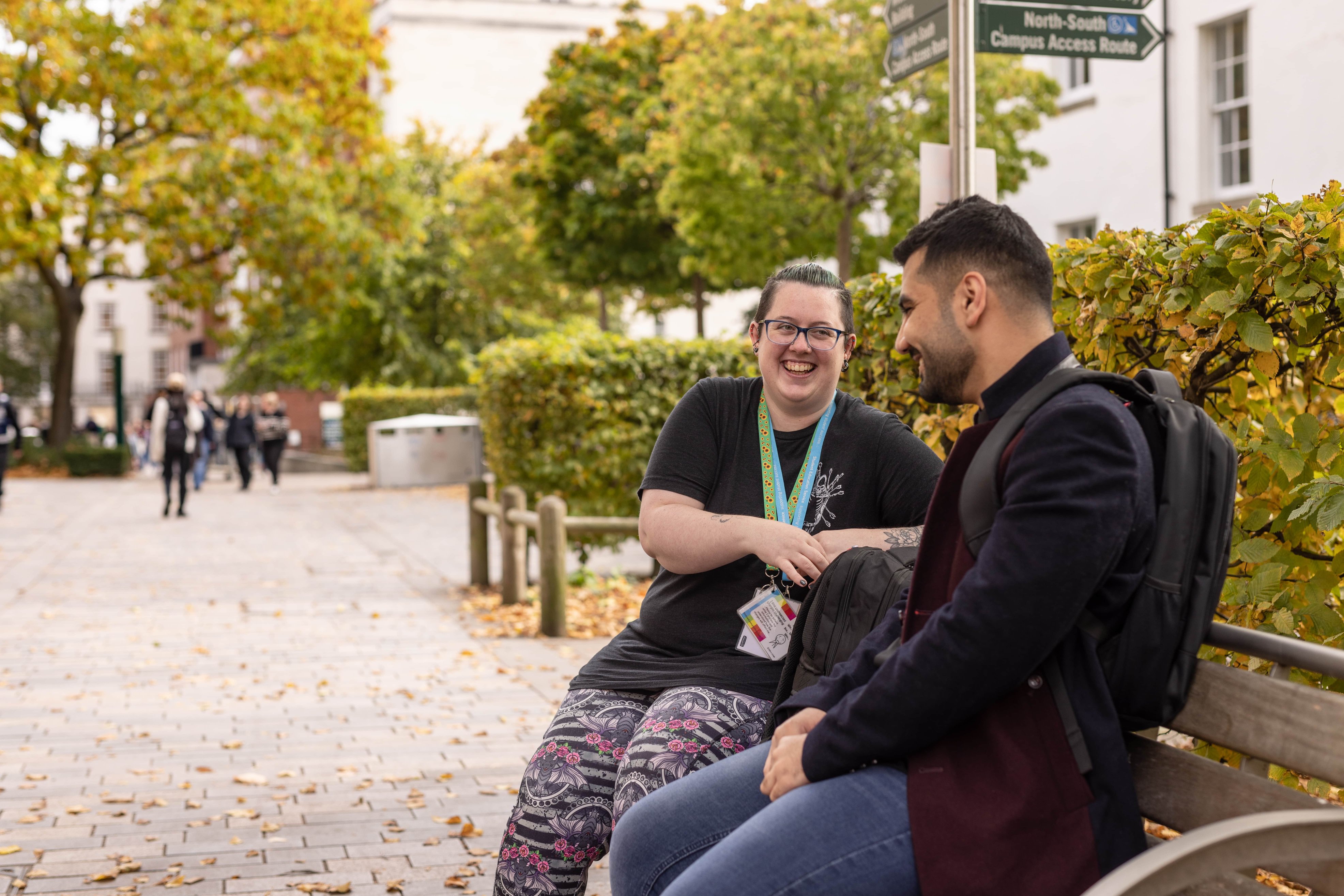 Man and woman smiling and chatting on a bench